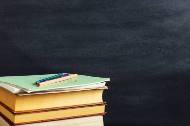 Kitaplar tebeşir tahtasının arka planında yatıyor. Çalışma kavramı veya öğretmenin günü. Kopyalama alanı.