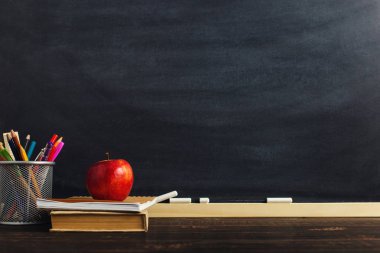 Yazma malzemeleri, bir kitap ve bir elma, metin için boş veya bir okul teması için bir arka plan ile Öğretmen masası. Kopyalama alanı.