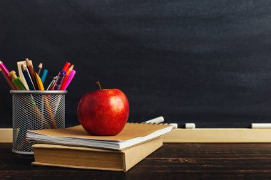 Yazma malzemeleri, bir kitap ve bir elma, metin için boş veya bir okul teması için bir arka plan ile Öğretmen masası. Kopyalama alanı.