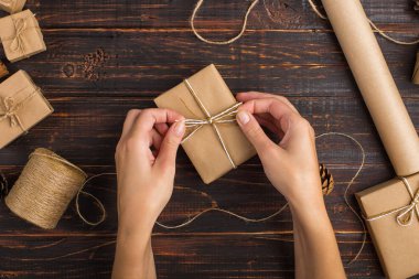 Kadın eli, el işi kağıdından bir hediye tutar. Kurumuş portakal, tarçın, kozalak, ahşap bir masada anason..