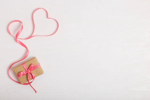 工艺纸和白色木桌上的粉红色丝带的礼物 文本的地方 复制空间 情人节明信片 — 图库照片