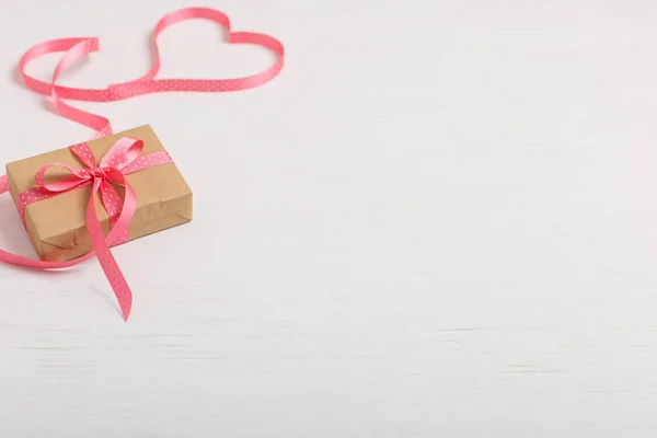 工艺纸和白色木桌上的粉红色丝带的礼物 文本的地方 复制空间 情人节明信片 — 图库照片