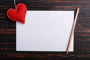 El yapımı kırmızı keçe kalp sonraki beyaz kağıt ahşap masa üzerinde. St. Valentine ve kadın gün, kopya alanı kavramı.
