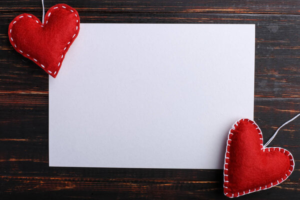 Handmade red felt heart next white paper on wooden table. The concept of St. Valentine and Women's Day, copy space.