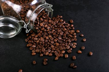 Hoş kokulu kahve çekirdekleri kavanoz rustik masa üstü arka plan üzerinde dağınık vardır. Afiş kopya alanı.