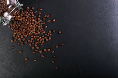 Hoş kokulu kahve çekirdekleri kavanoz rustik masa üstü arka plan üzerinde dağınık vardır. Afiş kopya alanı.