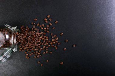 Hoş kokulu kahve çekirdekleri kavanoz rustik masa üstü arka plan üzerinde dağınık vardır. Afiş kopya alanı.