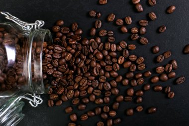 Hoş kokulu kahve çekirdekleri kavanoz rustik masa üstü arka plan üzerinde dağınık vardır. Afiş kopya alanı.