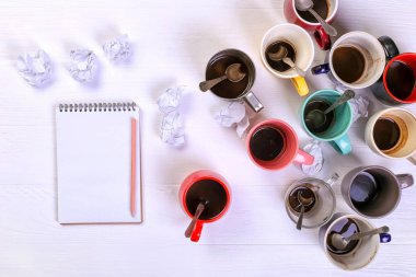 Boş kirli kahve fincanı, farklı renkler tablo ve defter mektup yazmak için. Kavram kafein uyarıcı, sorunu çözmek için enerji eksikliği. Kopya alanı.