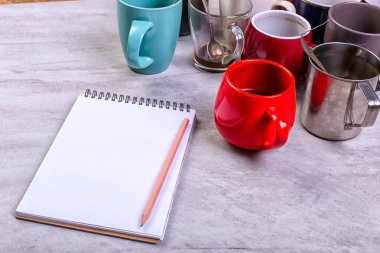 Boş kirli kahve fincanı, farklı renkler tablo ve defter mektup yazmak için. Kavram kafein uyarıcı, sorunu çözmek için enerji eksikliği. Kopya alanı.