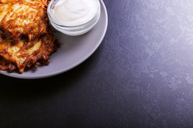 Hash brown ve ekşi krema de kızarmış karanlık bir taş zemin üzerine plaka üzerinde. Kopya alanı.