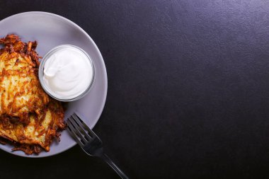 Hash brown ve ekşi krema de kızarmış karanlık bir taş zemin üzerine plaka üzerinde. Kopya alanı.