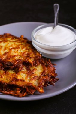 Hash brown ve ekşi krema de kızarmış karanlık bir taş zemin üzerine plaka üzerinde. Kopya alanı.