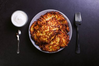 Hash brown ve ekşi krema de kızarmış karanlık bir taş zemin üzerine plaka üzerinde. Kopya alanı.