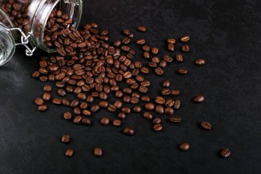 Hoş kokulu kahve çekirdekleri kavanoz rustik masa üstü arka plan üzerinde dağınık vardır. Afiş kopya alanı.