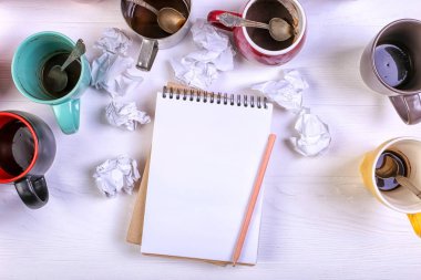 Boş kirli kahve fincanı, farklı renkler tablo ve defter mektup yazmak için. Kavram kafein uyarıcı, sorunu çözmek için enerji eksikliği. Kopya alanı.