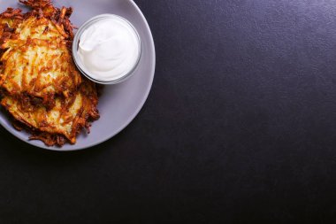 Hash brown ve ekşi krema de kızarmış karanlık bir taş zemin üzerine plaka üzerinde. Kopya alanı.