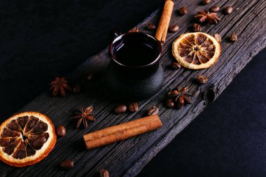 Bir fincan kahve, yıldız anason, tarçın, portakal ve kahve fasulye karanlık mutfak tezgah üzerinde kurumuş. İçki, yakın çekim, üstten görünüm, düz ley güzel kokulu baharatlar.