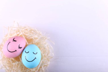 Mavi ve pembe yumurta yuvada, kopya alanı boyalı gülümsüyor. Mutlu Paskalya kavramı, tebrik kartı tasarımı.