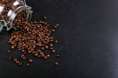 Hoş kokulu kahve çekirdekleri kavanoz rustik masa üstü arka plan üzerinde dağınık vardır. Afiş kopya alanı.