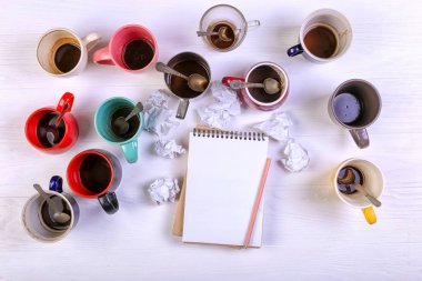 Boş kirli kahve fincanı, farklı renkler tablo ve defter mektup yazmak için. Kavram kafein uyarıcı, sorunu çözmek için enerji eksikliği. Kopya alanı.