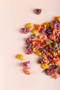 Doğal bitkisel boya ilavesi ile çok renkli makarna. Sarı arka plan üzerinde dağınık. Üstten Görünüm, desen.