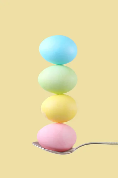 Самка Держит Ложку Которой Сбалансированы Разноцветные Яйца Желтом Фоне Необычный — стоковое фото