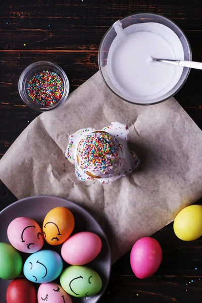 Пасхальная выпечка с глазурью и цветной порошок и яйца. Подготовка к празднику на кухонном столе, на темном фоне . — стоковое фото
