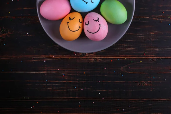 Пасхальні яйця з милими обличчями на тарілці. Підготовка до свята на кухонному столі, на темному тлі, копіювання простору . — стокове фото
