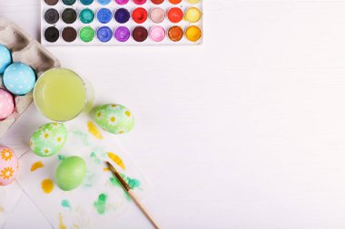 El boyalı Paskalya yumurta, boyalar ve fırçalar beyaz bir tablo. Tatil için hazırlık.