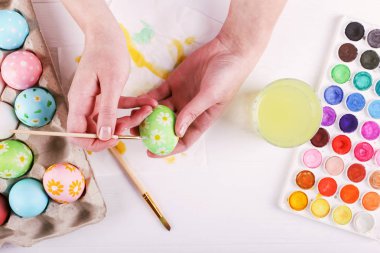 El boyalı Paskalya yumurta, boyalar ve fırçalar beyaz bir tablo. Tatil için hazırlık. Kızlar el bir desen çizmek.