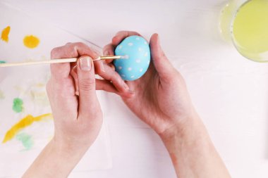 El boyalı Paskalya yumurta, boyalar ve fırçalar beyaz bir tablo. Tatil için hazırlık. Kızlar el bir desen çizmek.