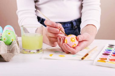 El boyalı Paskalya yumurta, boyalar ve fırçalar beyaz bir tablo. Tatil için hazırlık. Kızlar el bir desen çizmek.