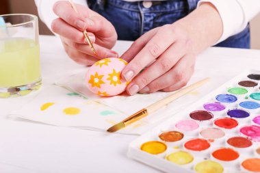 El boyalı Paskalya yumurta, boyalar ve fırçalar beyaz bir tablo. Tatil için hazırlık. Kızlar el bir desen çizmek.