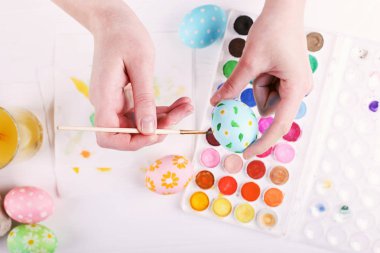 El boyalı Paskalya yumurta, boyalar ve fırçalar beyaz bir tablo. Tatil için hazırlık. Kızlar el bir desen çizmek.