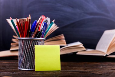 Defter, kitap açın ve kalemler tebeşir tahtası arka plan üzerinde koyu ahşap bir masa üzerinde durmak. Okulda, etiket kopya alanı bilgi öğrenme.