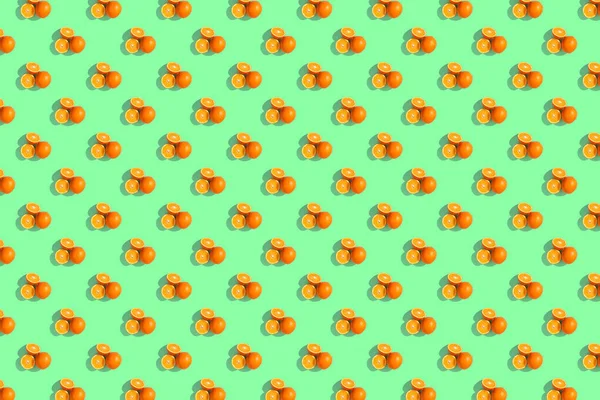 Sinaasappelen op een fel gekleurde groene achtergrond. Herhalend patroon, — Stockfoto