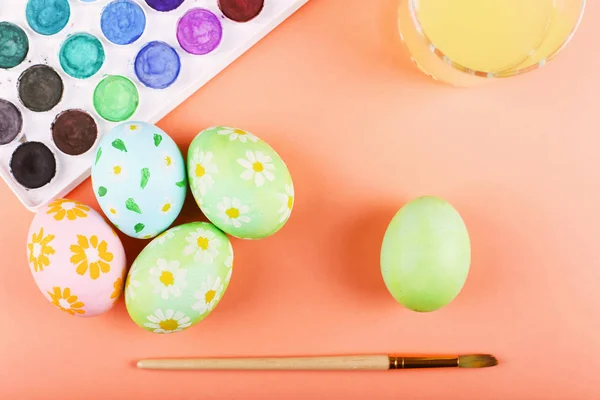 Рука розмальовувала великодні яйця, фарби та пензлі на столі. Підготовка до свята . — стокове фото