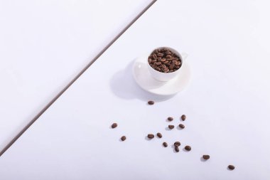 Seramik kupa kahve çekirdekleri, üzerinde beyaz bir arka plan ile. Sert 
