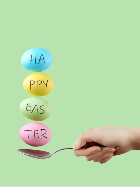 Female hand holds a spoon on which multi-colored eggs are balanc — Stock Photo, Image