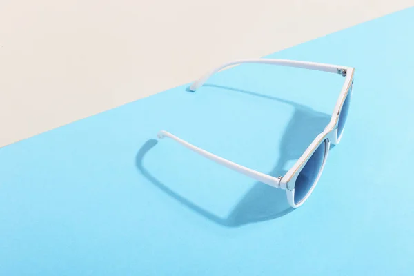 Las gafas de sol se encuentran sobre un fondo de color que proyecta una sombra áspera, arte conceptual de verano y relajación, minimalismo . —  Fotos de Stock