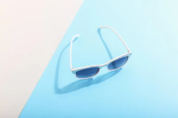 Las gafas de sol se encuentran sobre un fondo de color que proyecta una sombra áspera, arte conceptual de verano y relajación, minimalismo . —  Fotos de Stock