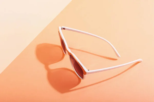 Las gafas de sol se encuentran sobre un fondo de color que proyecta una sombra áspera, arte conceptual de verano y relajación, minimalismo . —  Fotos de Stock