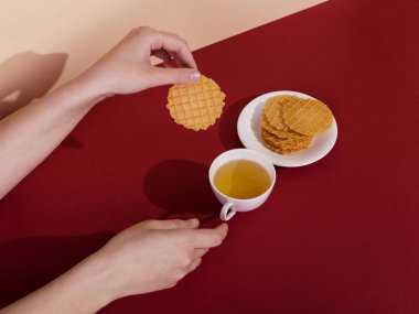 Seramik bardak çay ve gözleme, kırmızı bir arka plan ile. Güneş, sabah sanat kavramı ve enerji şarj sert gölgesinde. Kız el için kupa ulaşır.