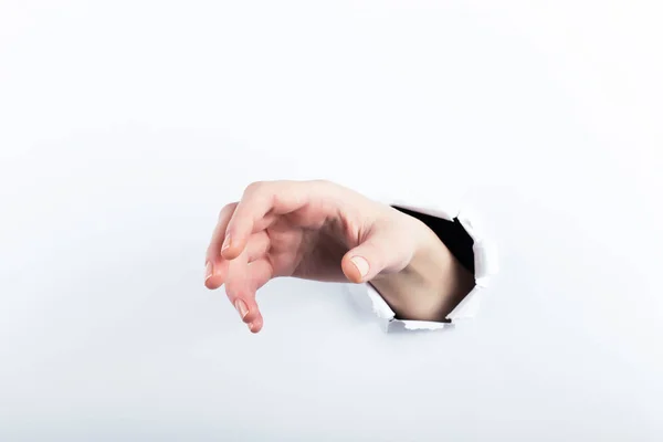 Weibliche Hand aus dem Loch im Papier. isolieren auf weißem Hintergrund. — Stockfoto