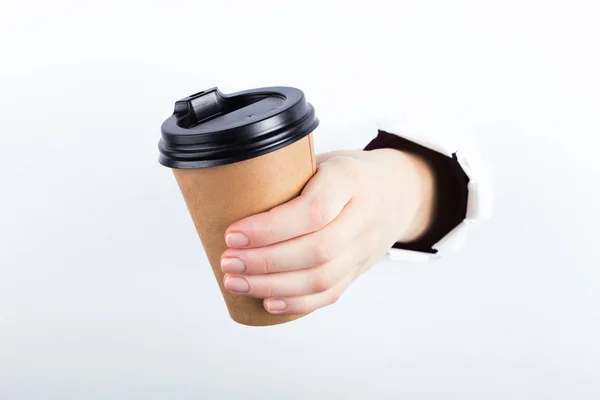 Vrouwelijke hand uit het gat in de paperman, houdt een bruinglas koffie met hem. Isoleren op witte achtergrond. — Stockfoto