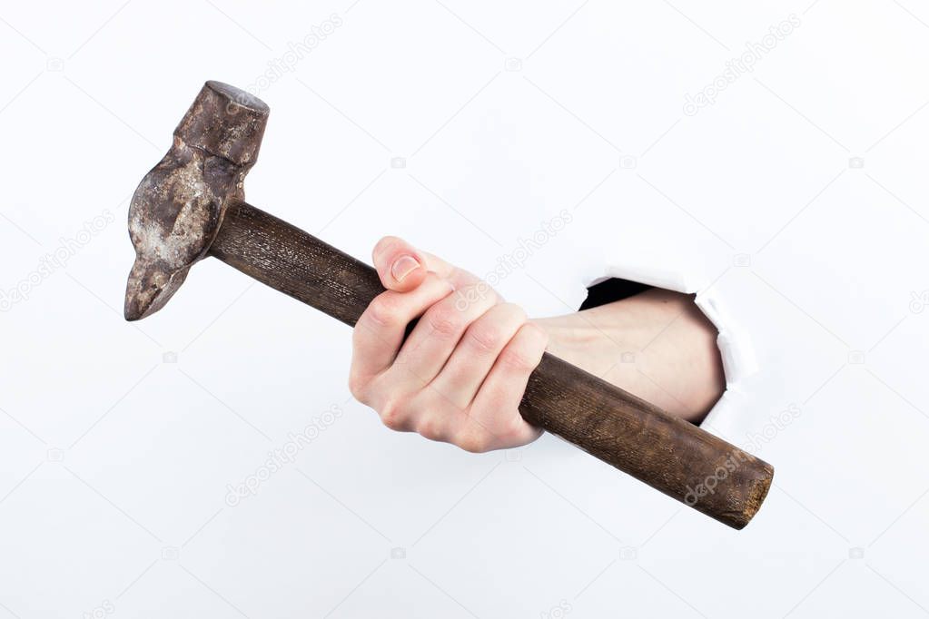 Female hand out of a hole in paper, holding a hammer. Isolate on white background.