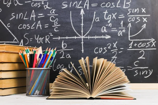 Schulbank im Klassenzimmer, mit Büchern auf dem Hintergrund einer Kreidetafel mit geschriebenen Formeln. Soncept Lehrertag. — Stockfoto