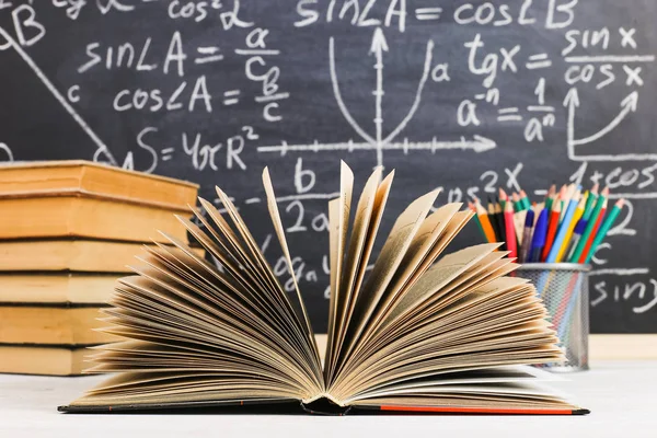 Biurko w klasie, z książek na tle tablicy kredą napisał formuł. Dzień nauczyciela Soncept. — Zdjęcie stockowe