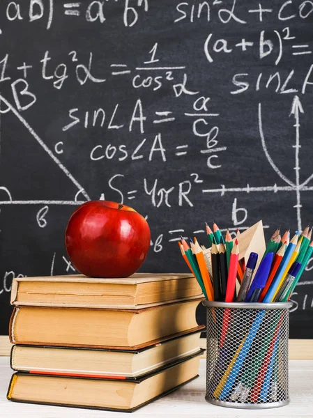 Schulbank im Klassenzimmer, mit Büchern auf dem Hintergrund einer Kreidetafel mit geschriebenen Formeln. Soncept Lehrertag. — Stockfoto